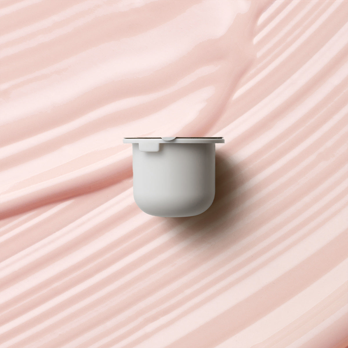 KORA Organics Kakadu Plum Vitamin C Eye Cream refill pod on a soft pink cream-texture background