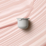 KORA Organics Kakadu Plum Vitamin C Eye Cream refill pod on a soft pink cream-texture background