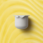 KORA Organics Turmeric Glow Moisturiser refill pod on a golden cream-texture background