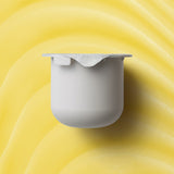 KORA Organics Turmeric Glow Moisturiser refill pod set against a golden yellow cream texture.