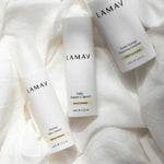 Three white LAMAV Brightening Skin Discovery products arranged on softly draped white fabric, including cleanser, vitamin C serum and correcting cream.