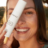 Smiling woman wearing LAMAV Organic BB Cream and holding the tube