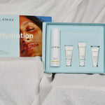 Open pale blue LAMAV Hydration Skin Discovery Pack displaying one white bottle and three small tubes on draped white fabric.