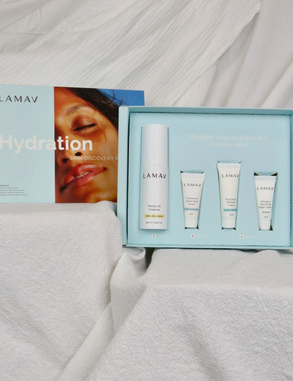 Open pale blue LAMAV Hydration Skin Discovery Pack displaying one white bottle and three small tubes on draped white fabric.