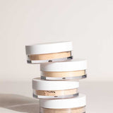 Stack of four open LAMAV Anti Ageing Mineral Foundation SPF 15 pots showing different powder shades on a neutral surface.