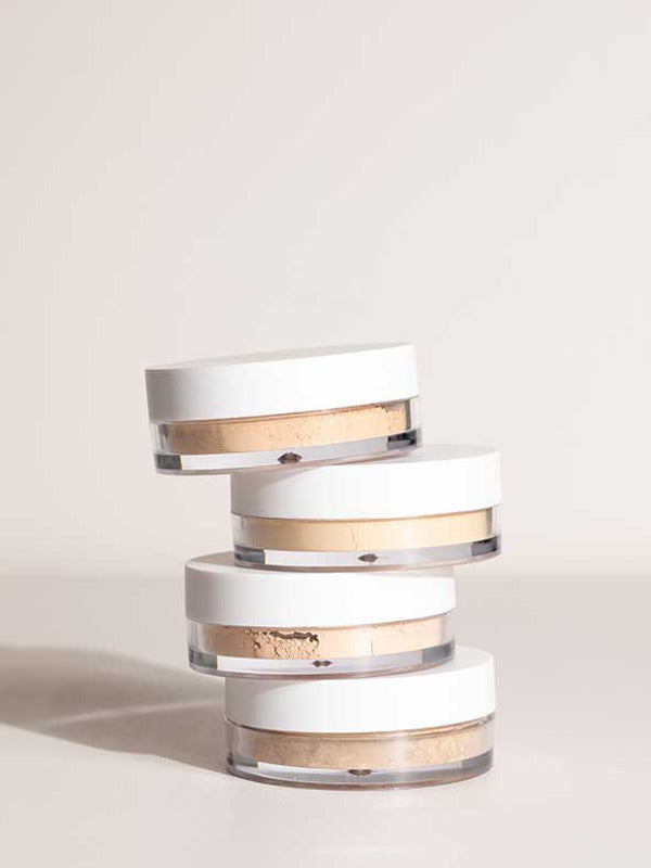 Stack of four open LAMAV Anti Ageing Mineral Foundation SPF 15 pots showing different powder shades on a neutral surface.