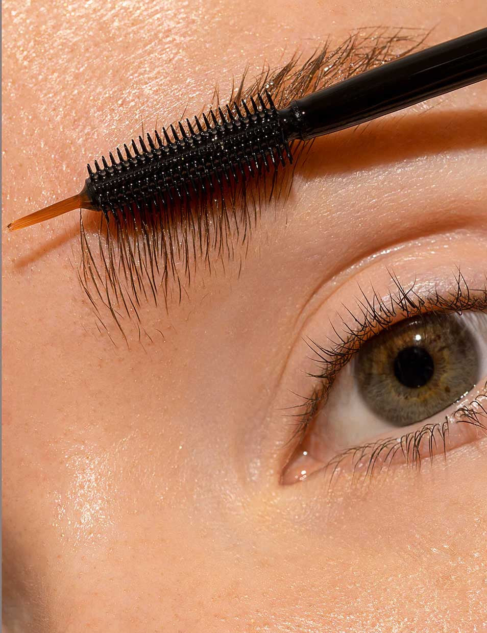 A close-up of a person’s eye as their eyebrow is groomed with a spoolie, featuring INIKA Organic Lash and Brow Serum 7ml for smooth skin and well-defined brows.