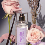 Lavanila Healthy Hair and Body Mist in Vanilla Lavender styled with pink roses, lavender stems, vanilla pods and a lilac flower.