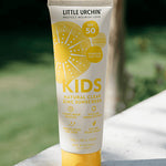 Little Urchin Kids Natural Clear Zinc Sunscreen SPF50+ 100g — the yellow 100g tube standing outdoors in sunlight.