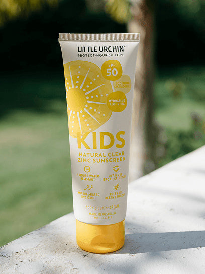 Little Urchin Kids Natural Clear Zinc Sunscreen SPF50+ 100g — the yellow 100g tube standing outdoors in sunlight.