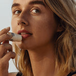 Woman applying Little Urchin tropical pawpaw lip balm