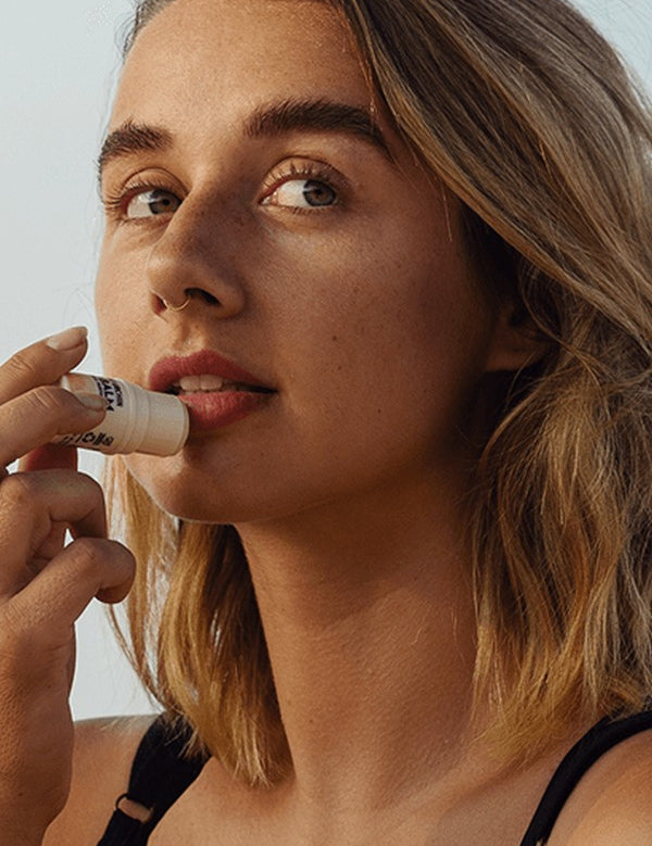 Woman applying Little Urchin tropical pawpaw lip balm