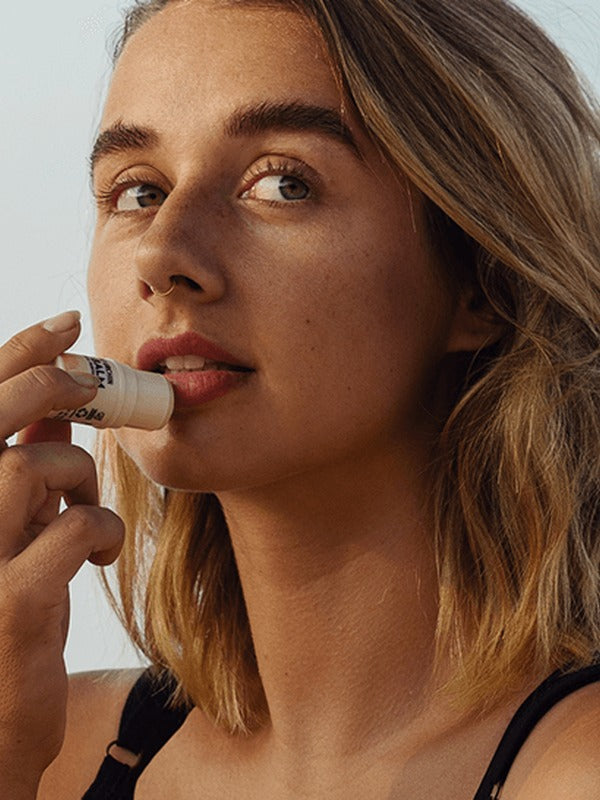 Woman applying Little Urchin tropical pawpaw lip balm