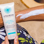 Little Urchin Natural Clear Zinc Sunscreen SPF30 100g — the 100g tube held beside an arm with sunscreen spread across the skin.
