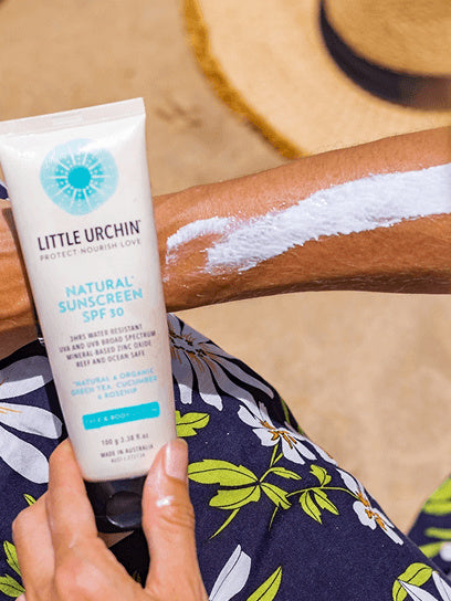 Little Urchin Natural Clear Zinc Sunscreen SPF30 100g — the 100g tube held beside an arm with sunscreen spread across the skin.