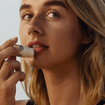 Little Urchin Tropical Pawpaw Lip Balm 4g: a woman applying the tropical pawpaw lip balm to her lips.