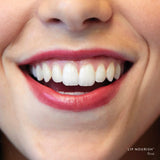 Close-up of a smile wearing Rosé Lip Nourish, showing a sheer wine-red lip colour with a glossy finish.