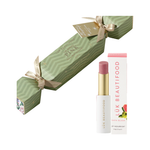 Luk Beautifood Bon Bon Guava Blush Lipstick Cracker on white: light green Christmas cracker tied with gold ribbons, alongside an open pink lipstick and its white carton.