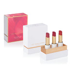 Luscious Reds Lip Nourish Trio with three uncapped red-toned lipsticks in an open white and gold box, beside the white lid and pink-and-gold outer sleeve.