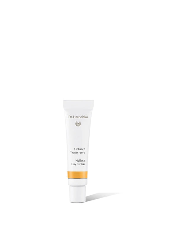 Small white Dr Hauschka Melissa Day Cream tube with a white cap and a golden-yellow band, standing upright and casting a shadow to the right.