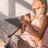 Woman relaxing with her cat in official Melrose FutureLab Deep Wave Sleep Booster lifestyle imagery
