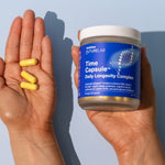 Hands holding Melrose FutureLab Time Capsule and daily capsules against a blue background