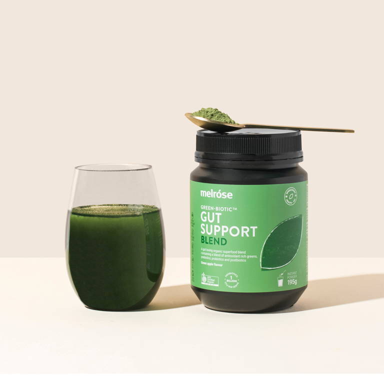 Melrose Green-Biotic Gut Support Blend styled with a prepared green drink and spoonful of powder.