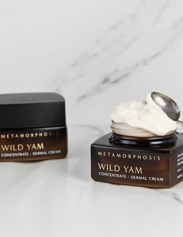 Metamorphosis Wild Yam Concentrate Dermal Cream jar, lid and small silver spoon arranged on pale marble.