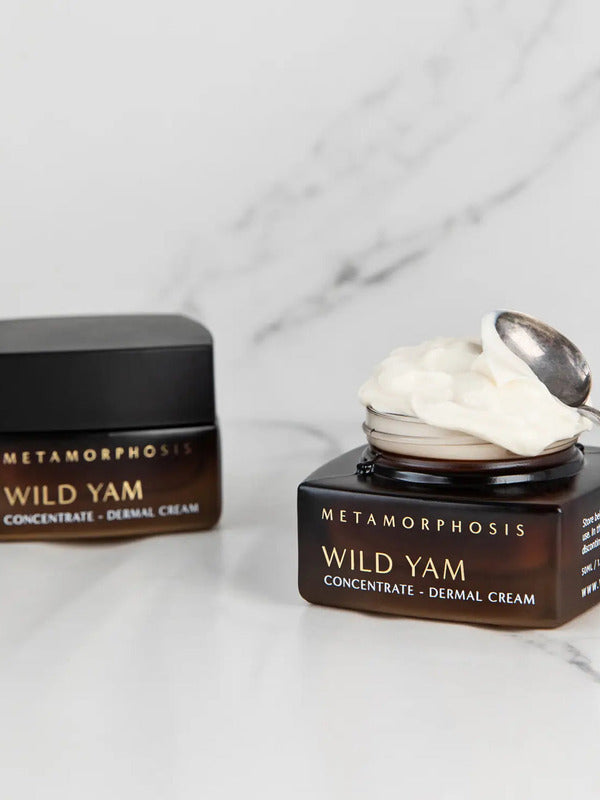 Metamorphosis Wild Yam Concentrate Dermal Cream jar, lid and small silver spoon arranged on pale marble.