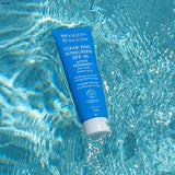 Blue MooGoo Baby Clear Zinc Sunscreen SPF 40 tube floating diagonally in bright rippling pool water.