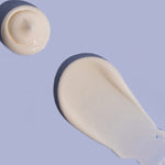 Small rounded dollop and broad smooth smear of off-white MooGoo Double Cream on a lilac background, casting dark shadows.