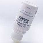 Uncapped MooGoo Natural Fresh Cream Deodorant Fragrance Free bottle tilted with the roller ball resting on a pale surface.