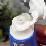 Clear gel toothpaste curling from an open blue MooGoo Kids Blueberry Smoothie Moothpaste tube held in a hand.