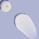 Small white dollop and a broad, smooth smear of MooGoo baby lotion on a lilac background, casting shadows along their raised edges.