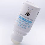 Uncapped white MooGoo Coconut Cream deodorant bottle tilted upside down with its exposed pale roller ball touching the surface.