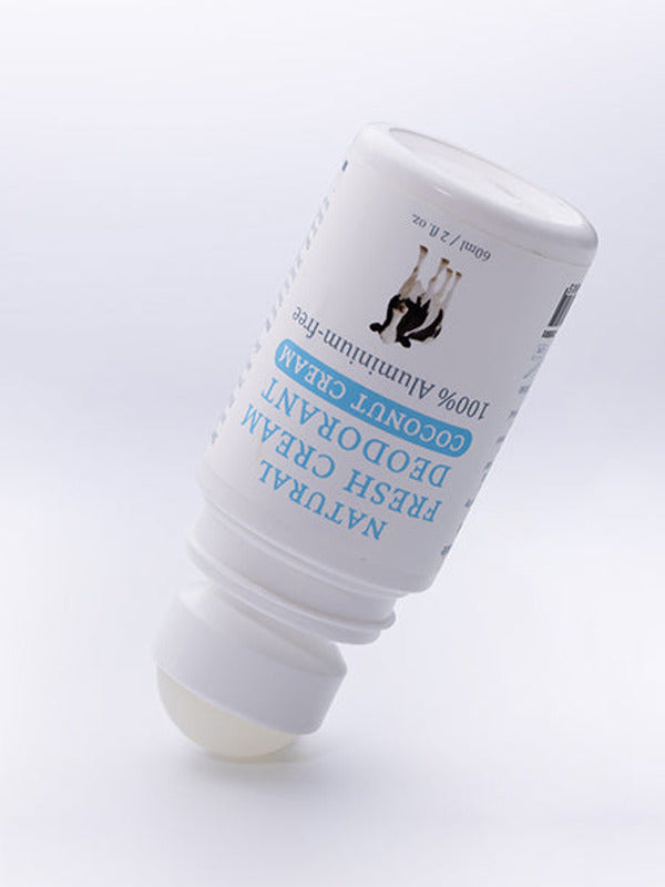 Uncapped white MooGoo Coconut Cream deodorant bottle tilted upside down with its exposed pale roller ball touching the surface.