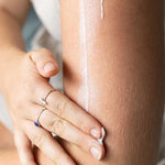 Close-up of a hand rubbing moisturiser into an arm, with a long white streak of cream visible above the hand.