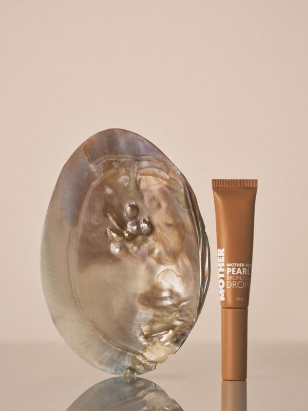 MOTHER SPF Mother of Pearl Bronzing Drops styled with a pearl shell