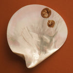 MOTHER SPF bronzing drops styled with an oyster shell
