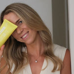 Woman holding MOTHER SPF Face and Body sunscreen