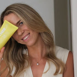 Woman holding MOTHER SPF Face and Body sunscreen