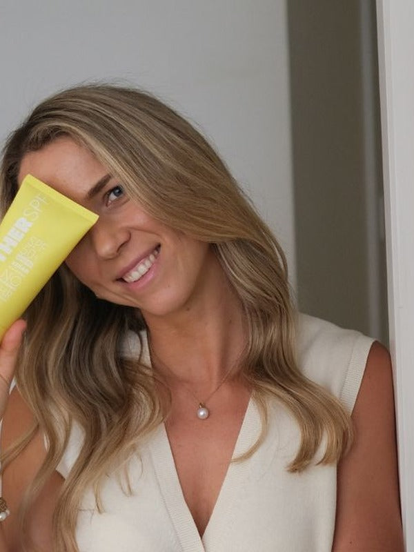 Woman holding MOTHER SPF Face and Body sunscreen