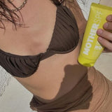 MOTHER SPF Face and Body sunscreen held in the sun