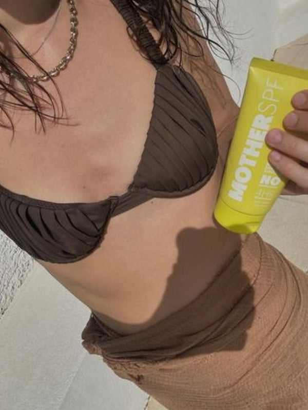 MOTHER SPF Face and Body sunscreen held in the sun