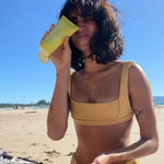 Woman using MOTHER SPF Face and Body sunscreen at the beach