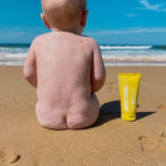 MOTHER SPF Face and Body sunscreen beside a baby at the beach