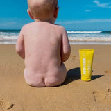 MOTHER SPF Face and Body sunscreen beside a baby at the beach