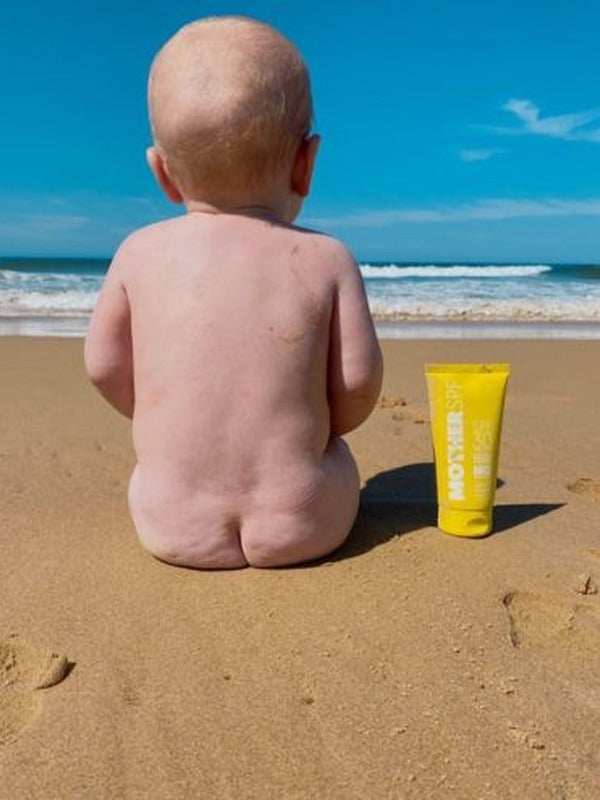 MOTHER SPF Face and Body sunscreen beside a baby at the beach