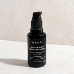 Mukti Golden Glow Bronzing Drops 30ml black pump bottle standing on a pale stone surface with its front label visible.