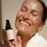 Smiling woman holding Mukti Bioactive Renewal Day Serum